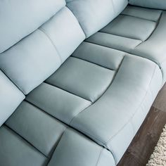 a blue leather couch sitting on top of a wooden floor next to a white rug