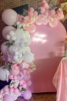 the balloon arch is decorated with white and pink balloons, greenery, and baby's breath flowers