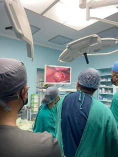 doctors in scrubs and surgical masks looking at an x - ray