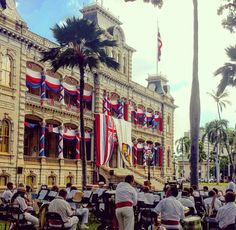 a group of people sitting around tables in front of a building with flags on it