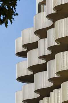 the side of a tall building with curved metal balconies