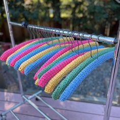 a rack that has some clothes hanging on it and is filled with colorful yarns