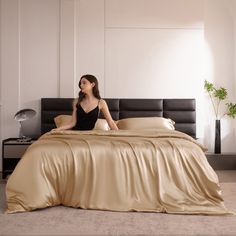 a woman sitting on top of a bed next to a black headboard and foot board