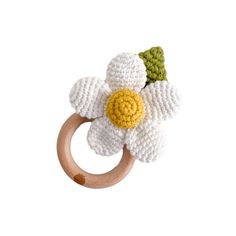 a crocheted wooden ring with a white flower on the front and green leaves on the back