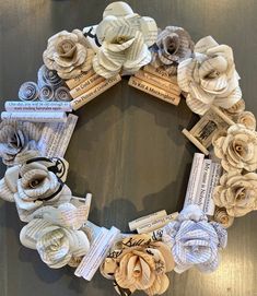 a wreath made out of old books and paper flowers is displayed on a wooden table