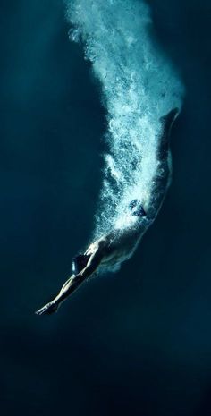 a man swimming in the ocean under a wave