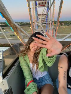 a man and woman sitting on top of a ferris wheel holding their hands up to the camera