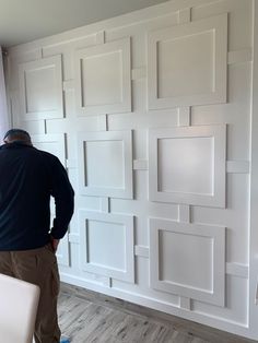 a man standing in front of a wall made out of white square shaped squares and rectangles