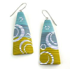 two pairs of earrings with blue, yellow and white designs on them sitting next to each other