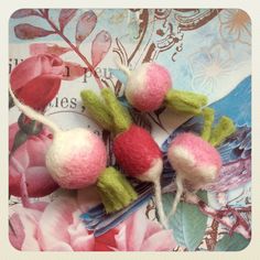 two needle - felted cherries are sitting on a piece of fabric with leaves and flowers