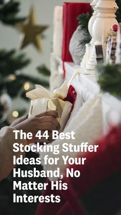 a person holding a present in front of a christmas tree with the words, the 4 best stocking stuff ideas for your husband, no matter his interest