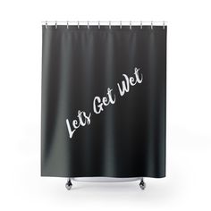 a black shower curtain with the words let's get wet written in white on it