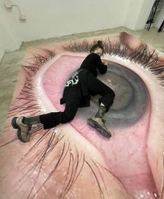 a woman laying on top of a giant fake eye