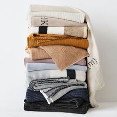 a stack of folded sweaters and scarves on top of each other in different colors