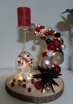 a candle and some ornaments are on a wooden stand next to a glass vase with a red candle in it