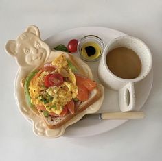 a white plate topped with a sandwich next to a cup of coffee