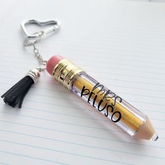 a pencil keychain with the word guess on it and a tassel attached to it