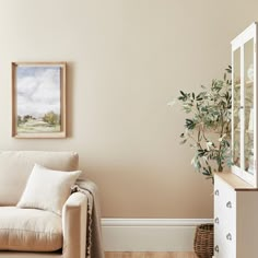 a white couch sitting next to a wooden dresser in a living room on top of a hard wood floor