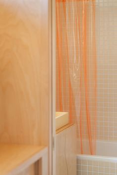 an orange shower curtain in a bathroom next to a bathtub and sink with wooden cabinets