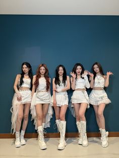 four girls in white outfits standing next to each other with their hands on their hips