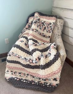 a crocheted blanket sitting on top of a couch next to a wooden wall