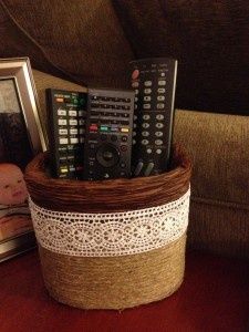 several remote controls are stacked in a basket on a table next to a framed photograph