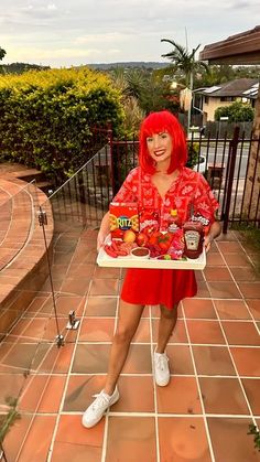 a woman with red hair holding a tray of fruit