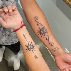 two people holding hands with tattoos on their arms and one has an arrow in the middle