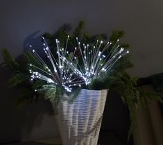 a white basket filled with christmas lights and greenery