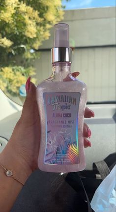 a woman holding up a bottle of hawaiian cologne