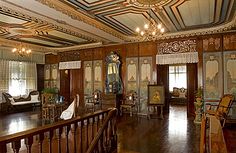 an ornately decorated living room with wood floors and walls, along with chandeliers