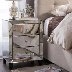 a mirrored night stand with three drawers and a magazine on the floor next to it