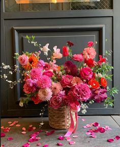 a basket filled with lots of pink and red flowers on top of a floor covered in confetti