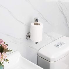 a white toilet sitting next to a sink under a bathroom towel dispenser