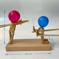 a wooden toy with two balloons attached to it's sides and an arrow on the other side