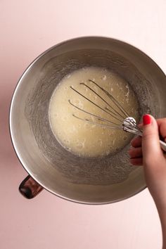 a woman whisk batter into a metal bowl