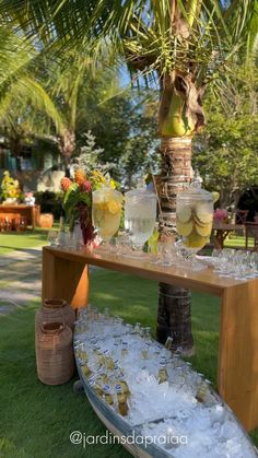 an outdoor table with drinks and ice on it in front of a palm tree at a party