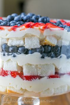 a layered cake with berries, blueberries and cream cheesecake filling is on a glass plate