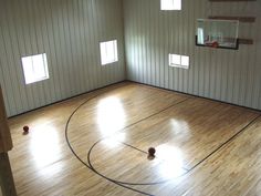 an indoor basketball court with hard wood flooring and white walls, along with windows