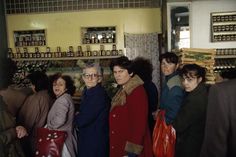 a group of people standing around each other in a room with shelves full of bottles