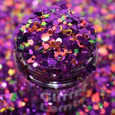 a jar filled with lots of purple and green confetti sprinkles