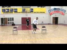 two young men playing basketball in a gym with one man standing on the sidelines