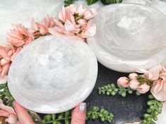 a woman's hand is holding two white plates with pink flowers on them and greenery