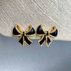 "Vintage Kenneth J. Lane for Avon Black Bow Earrings, Gold Tone Black Enamel Clip on Earrings, Designer Logo KJL Signed Jewelry, Gift for Her. Era: 1986-2000. Designer: K.J.L. for Avon ( Kenneth J. Lane) Measurements: - Length: 1 1/8\" inches. - Width: 1 1/8\" inches. Details: -Metal Color: Gold - Embellishments: Gold Tone Plating , Black Enamel, Ribbon Bow Shaped Earrings. - Closure: Clip On. Here are more Vintage Jewelry items for your viewing pleasure: https://etsy.me/2SGhTFo Our shop team me Gold Clip-on Costume Jewelry Earrings, Vintage Black Clip-on Earrings, Vintage Black Metal Clip-on Earrings, Vintage Enamel Clip-on Earrings, Antique Costume Jewelry, Vintage Jewelry Antique, Vintage Gold Clip-on Earrings With Black Enamel, Mineral Jewelry, Avon Jewelry