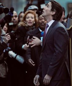 a man in a suit and tie surrounded by reporters