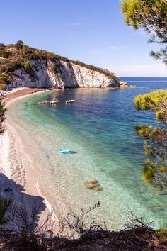 the beach is clear and blue with people on boats floating in the water near it