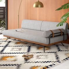 a couch sitting on top of a white rug next to a wooden table and lamp