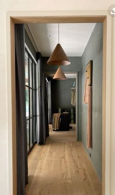 an open door leading to a hallway with wood flooring and curtains on the windows