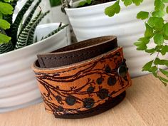 "I've made this wrapping cuff out of soft, scuffy brown and sienna brown leather. The leather has been hand printed with a design using indelible ink. Machine stitched, it has an attached elastic that hooks over a button, so this cuff will adjust to fit most wrist sizes 5.75\" to 7\" in circumference OR choose a custom size. At the narrowest, the width of the cuff is 1.25\" and at the widest it's 2\". Only premium quality leather and supplies are used to handcraft each item. Every item shipped i Brown Cuff Bracelet With Waxed Finish As Gift, Artisan Brown Leather Bracelet As Gift, Handmade Brown Leather Bracelet For Everyday, Artisan Brown Leather Bracelet For Gift, Artisan Brown Leather Bracelet Gift, Rustic Brown Cuff Bracelet As Gift, Brown Waxed Finish Cuff Bracelet As Gift, Hand Tooled Brown Leather Bracelet As Gift, Brown Cuff Bracelet With Waxed Finish For Gift