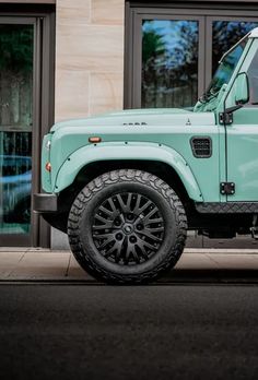 a mint green land rover is parked in front of a building